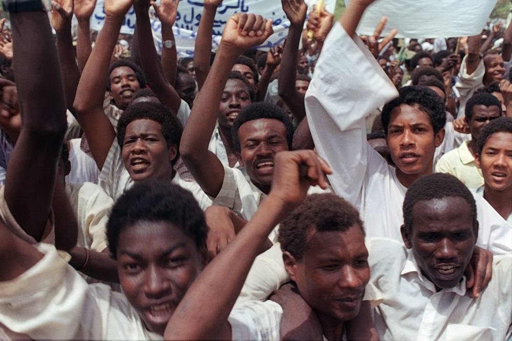 (FILES) In this file photo taken on July 11, 1989, supporters of Revolutionary Council ruler and military coup leader General Omar al-Bashir shout slogans during a pro-government rally in the Sudanese capital Khartoum, as Bashir took power after toppling the civilian government of Prime minister Sadiq Al-Mahdi in a coup on June 30, 1989. - Bashir was ousted on April 11, 2019 by the army after three decades of iron-fisted rule, but protestors swiftly rejected what they denounced as a coup by the regime and vowed to keep up their demonstrations. (Photo by MIKE NELSON / AFP)