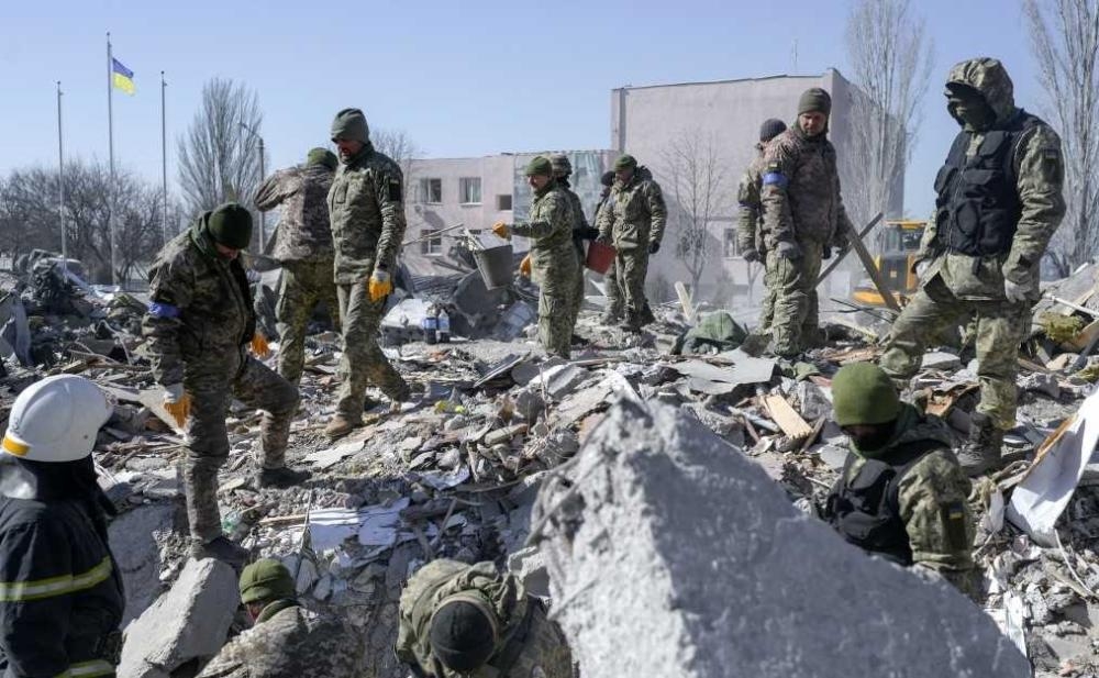 Ukrainian soldiers search for bodies in the debris at the military school hit by Russian rockets the day before, in Mykolaiv, southern Ukraine, on March 19, 2022. - Ukrainian media reported that Russian forces had carried out a large-scale air strike on Mykolaiv, killing at least 40 Ukrainian soldiers at their brigade headquarters. (Photo by BULENT KILIC / AFP)