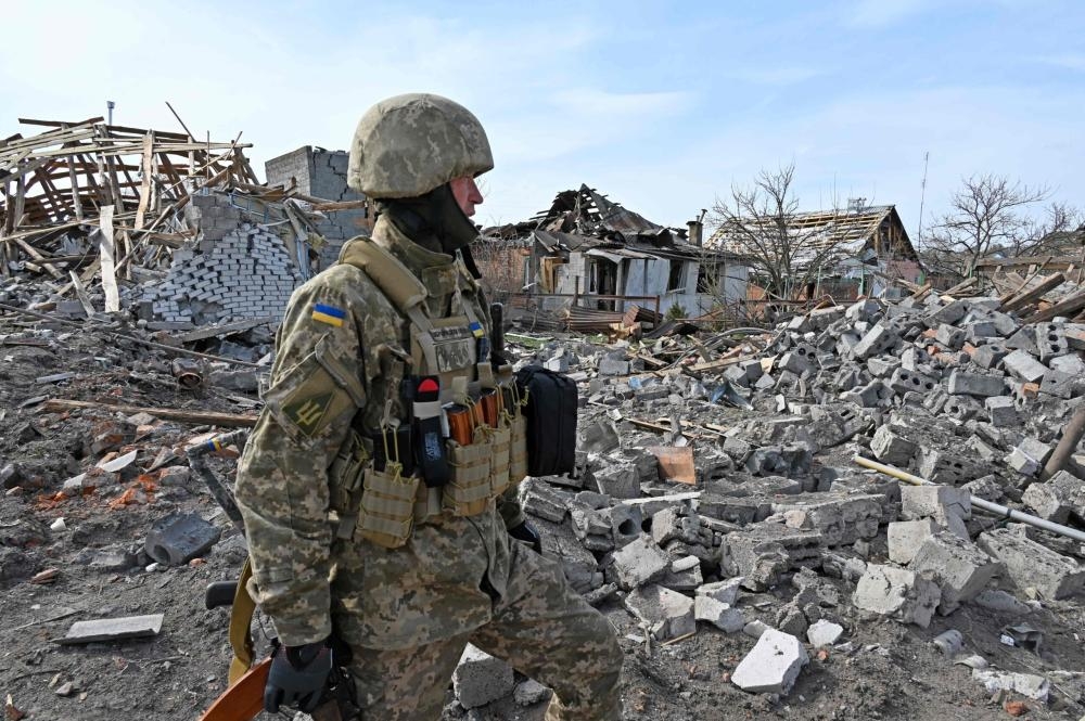 TOPSHOT - A Ukrainian serviceman looks at the rubble of destroyed houses in the outskirts of Chuguiv, Kharkiv region on April 8, 2022. (Photo by SERGEY BOBOK / AFP)
