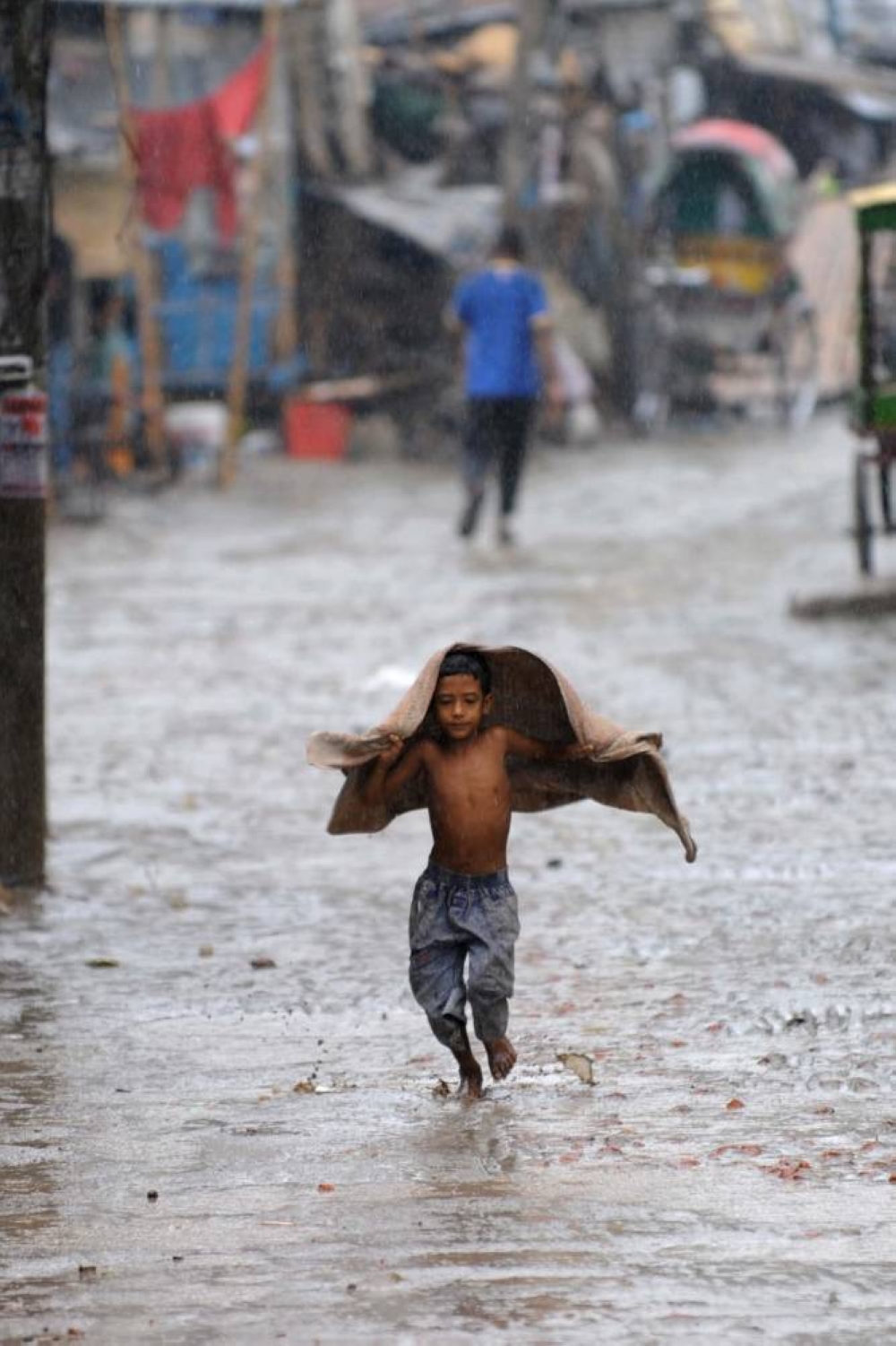 A Bangladeshi youth runs in the rain during a sudden downpour in Dhaka on July 9, 2009.  Seasonal rain has brought a whiff of relief to the Dhaka dwellers who have been experiencing dry and dusty weather amid power failures due to load shedding.  AFP PHOTO/Munir uz ZAMAN